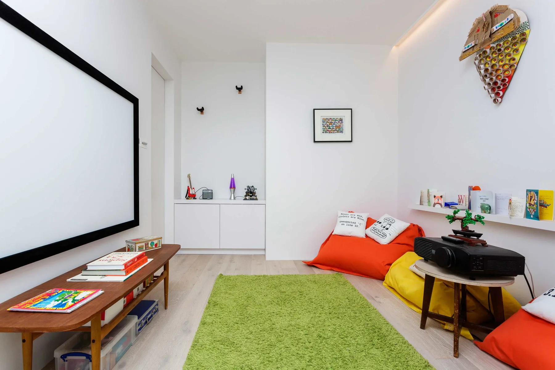 Una luminosa sala multimedia con una gran pantalla de proyección y cojines de colores.