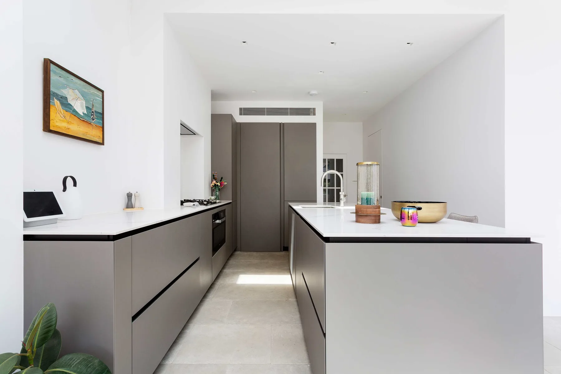 A bright modern kitchen with white countertops and dark cabinetry.