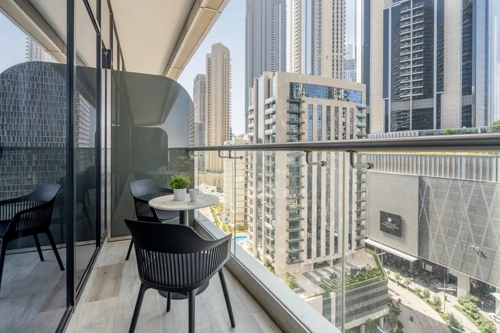 A balcony seating area overlooks nearby high-rise buildings.