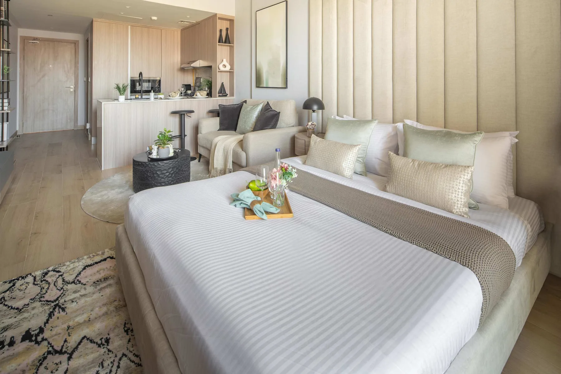 Un dormitorio luminoso con una cama tendida y una pequeña zona de estar.