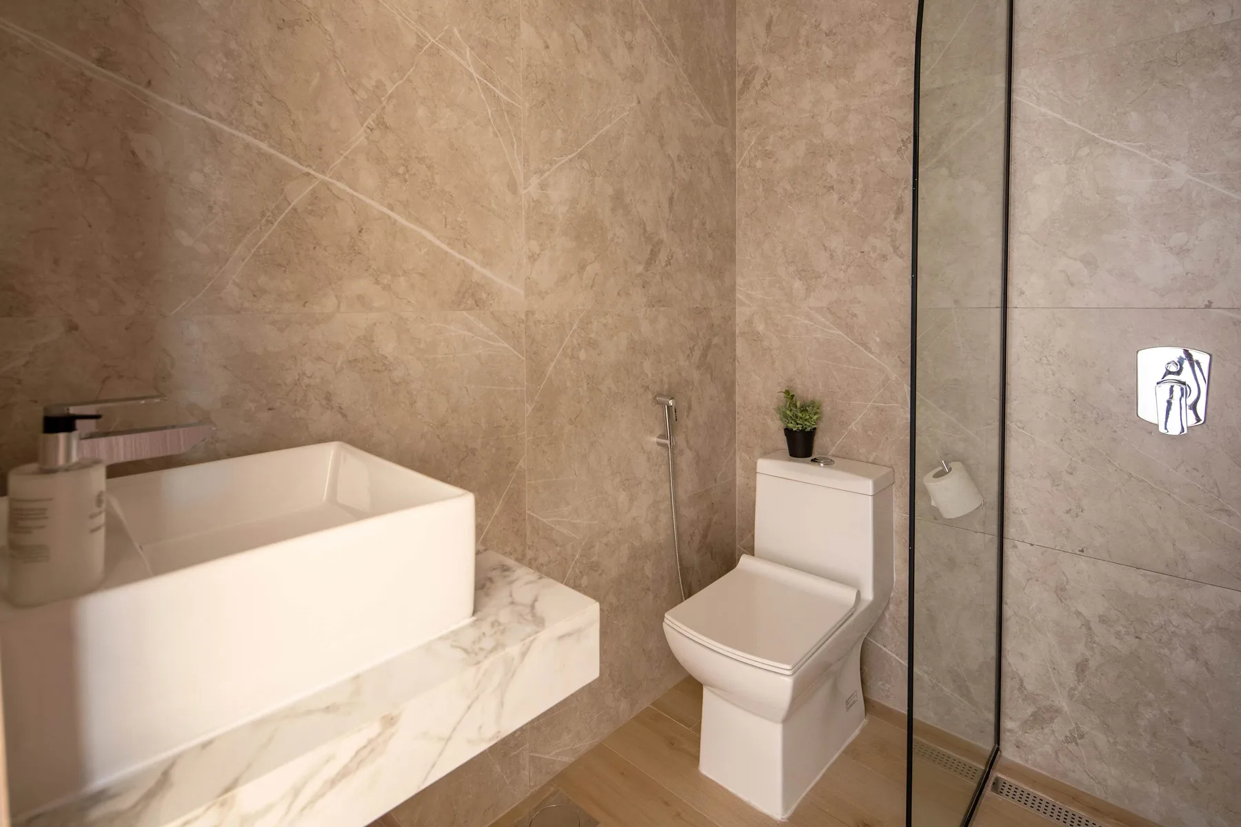Un baño moderno con lavabo rectangular, inodoro y mampara de ducha de vidrio.