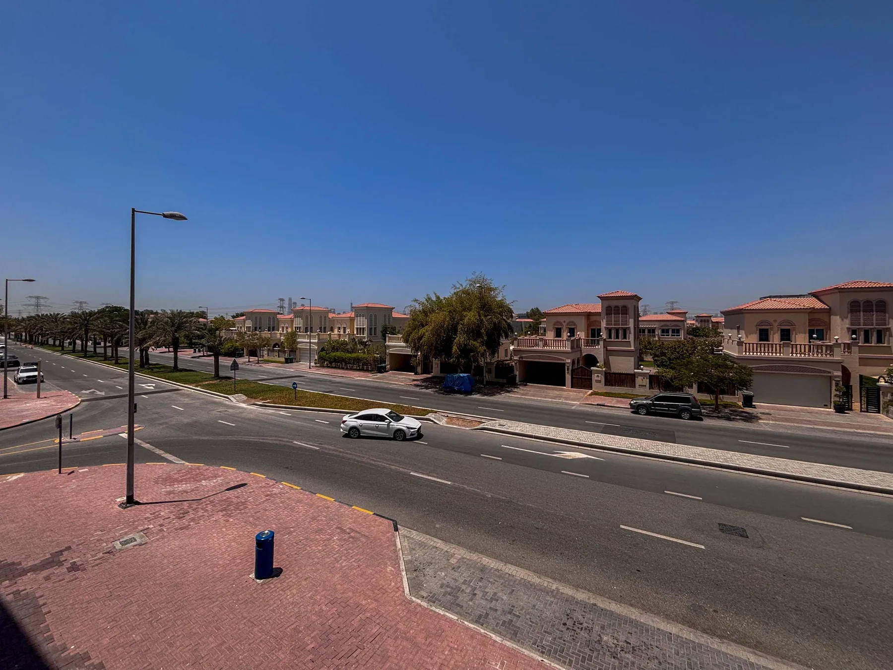 Una avenida amplia pasa junto a una hilera de edificios bajos bajo un cielo despejado.