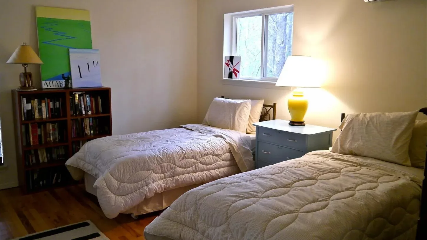 Un dormitorio con dos camas y una lámpara encendida junto a la ventana.