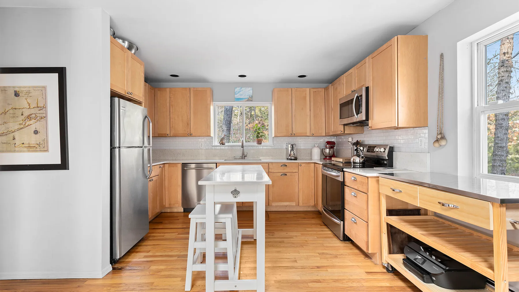 Una cocina luminosa con armarios de madera, electrodomésticos de acero inoxidable y una isla central.