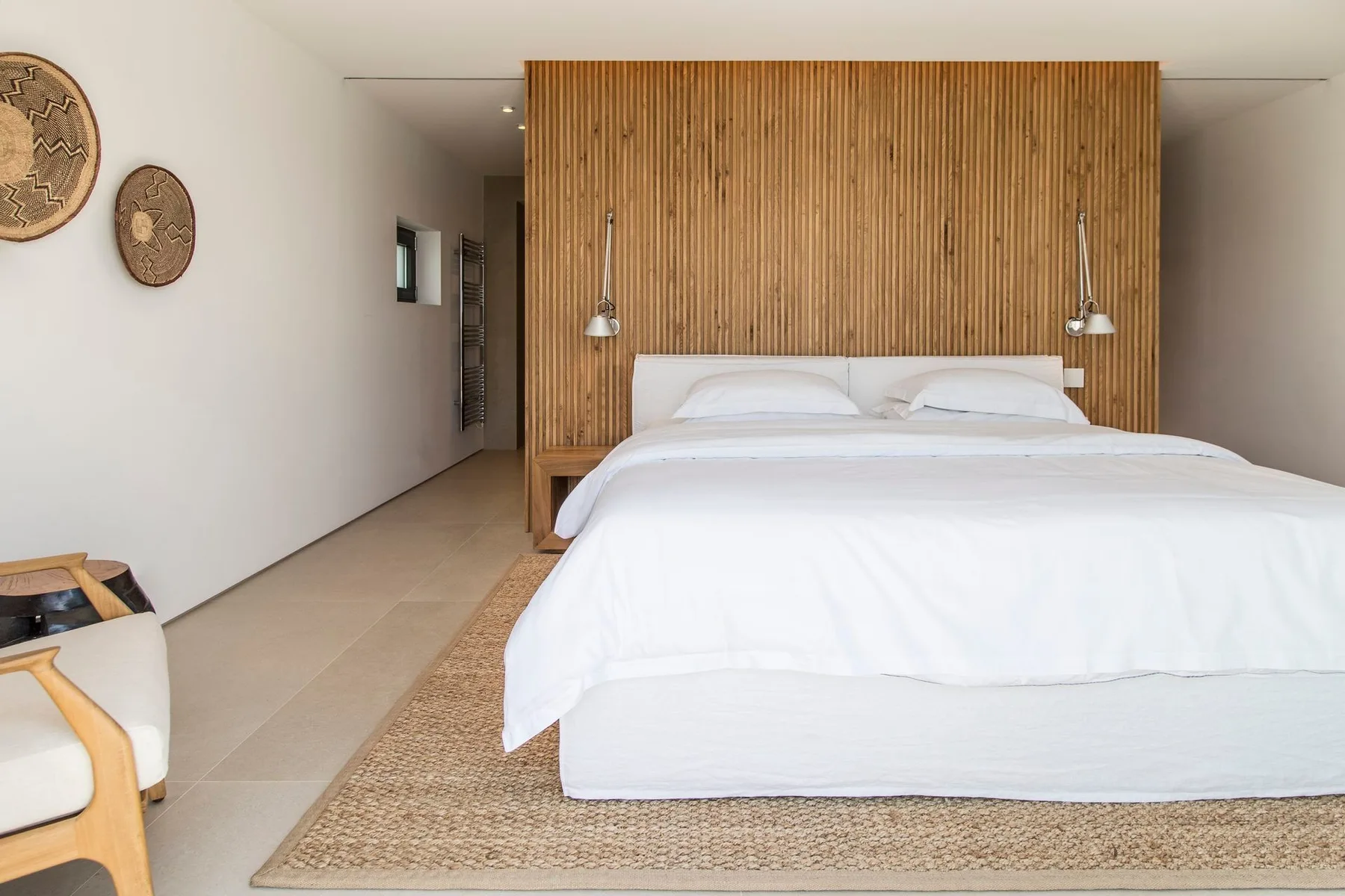 Un dormitorio con una cama frente a una pared con paneles verticales de madera.
