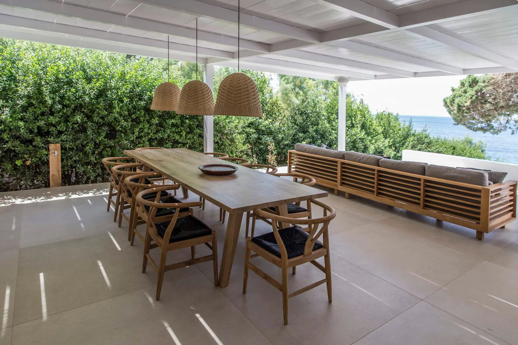 Comedor exterior cubierto con una mesa larga y asientos.
