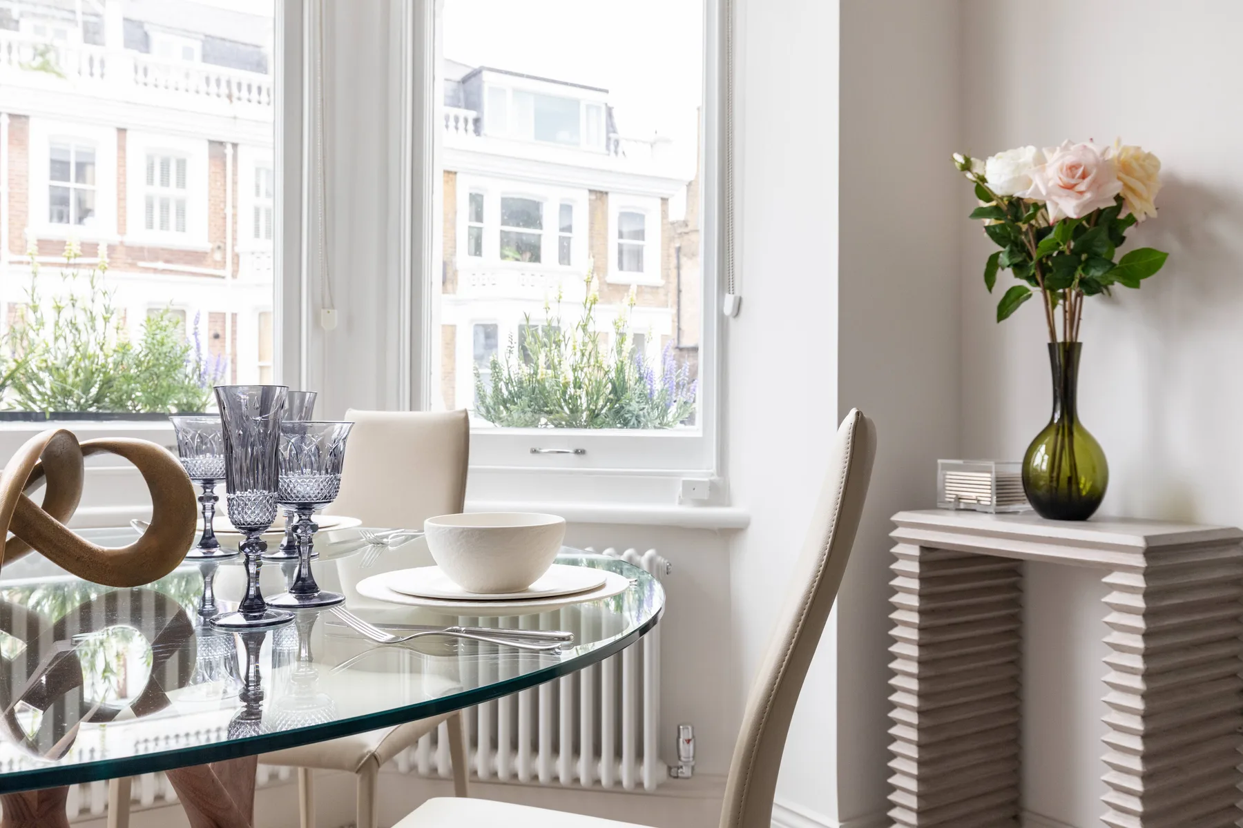 A bright dining area with a glass table set beside large windows.