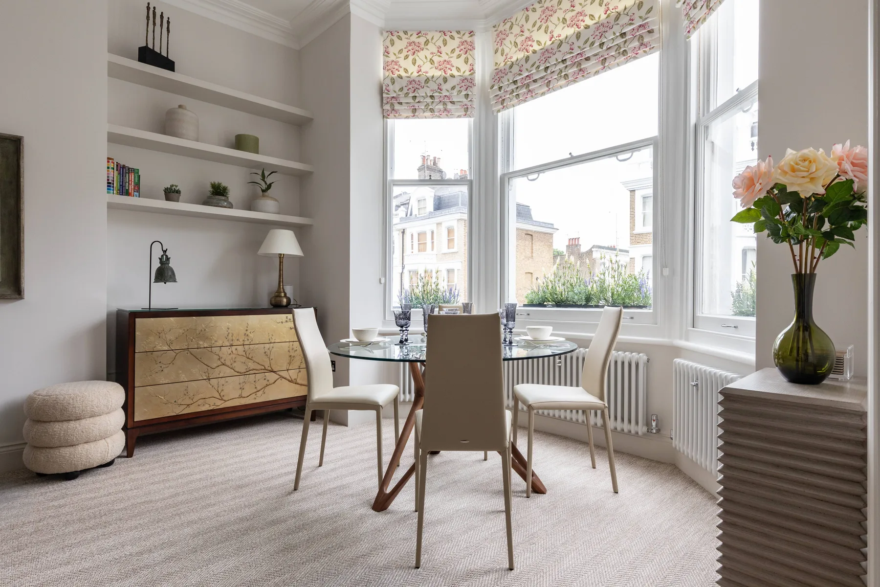 A bright dining area with a table and chairs beside large windows.
