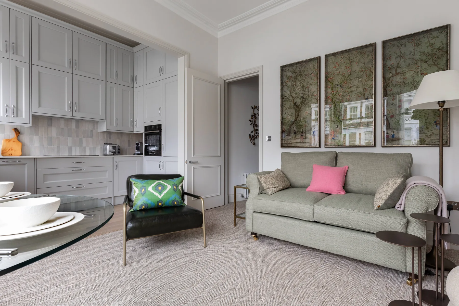 A bright living room with a gray sofa and an open kitchen.