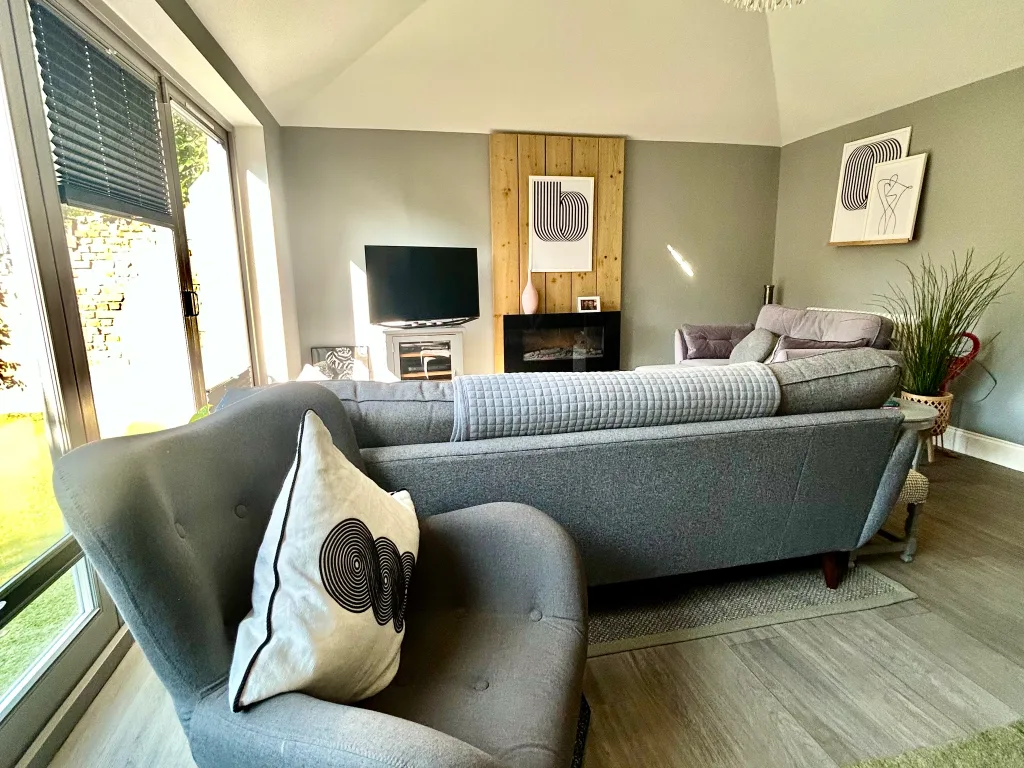 A living room with gray seating, framed artwork, and a fireplace.