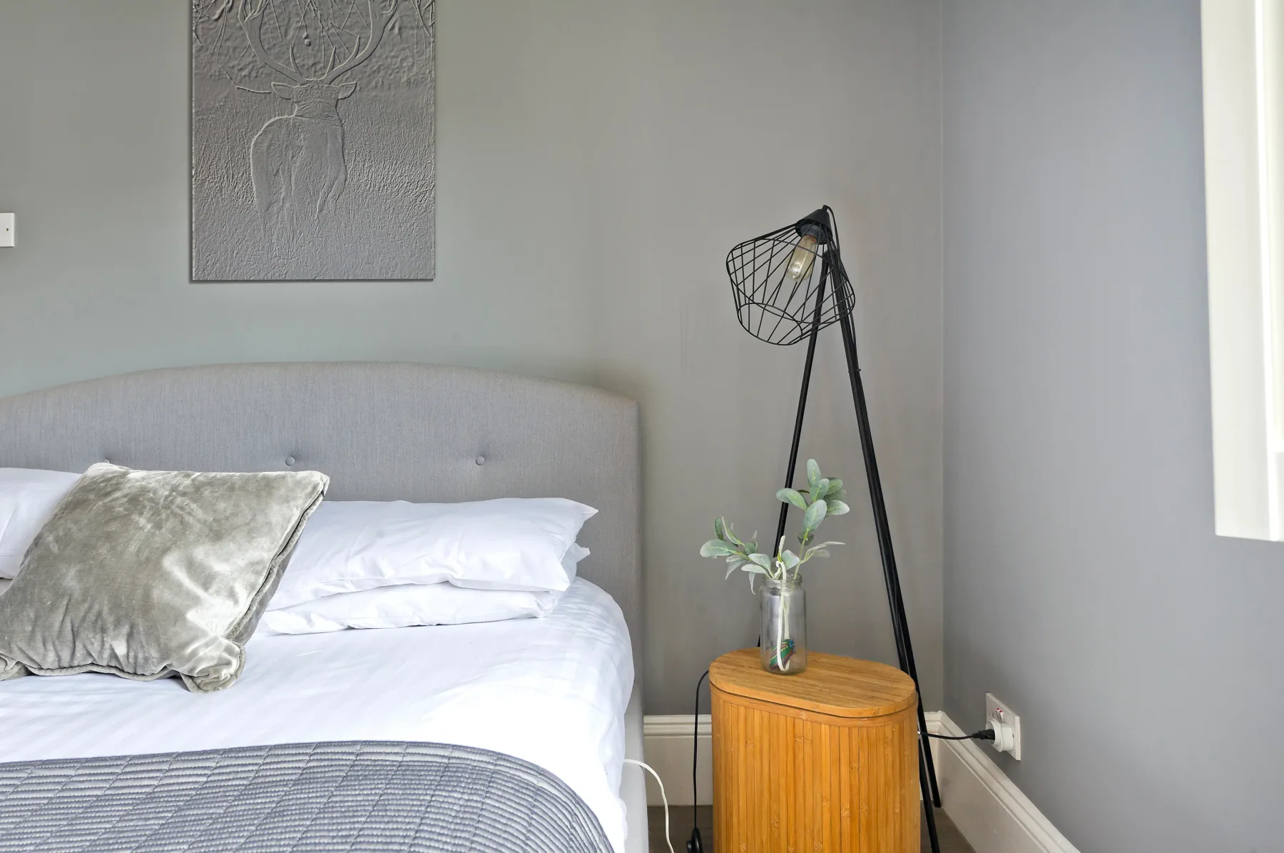 A bedroom with a neatly made bed and a small bedside table.