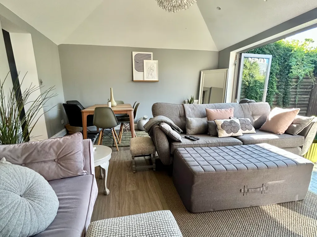 A bright living room with a sectional seating area and dining table by the windows.