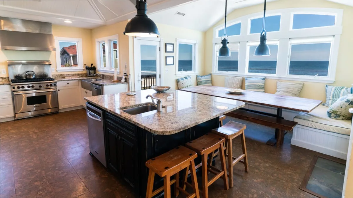 Una cocina luminosa con una isla central y asientos junto a las ventanas.