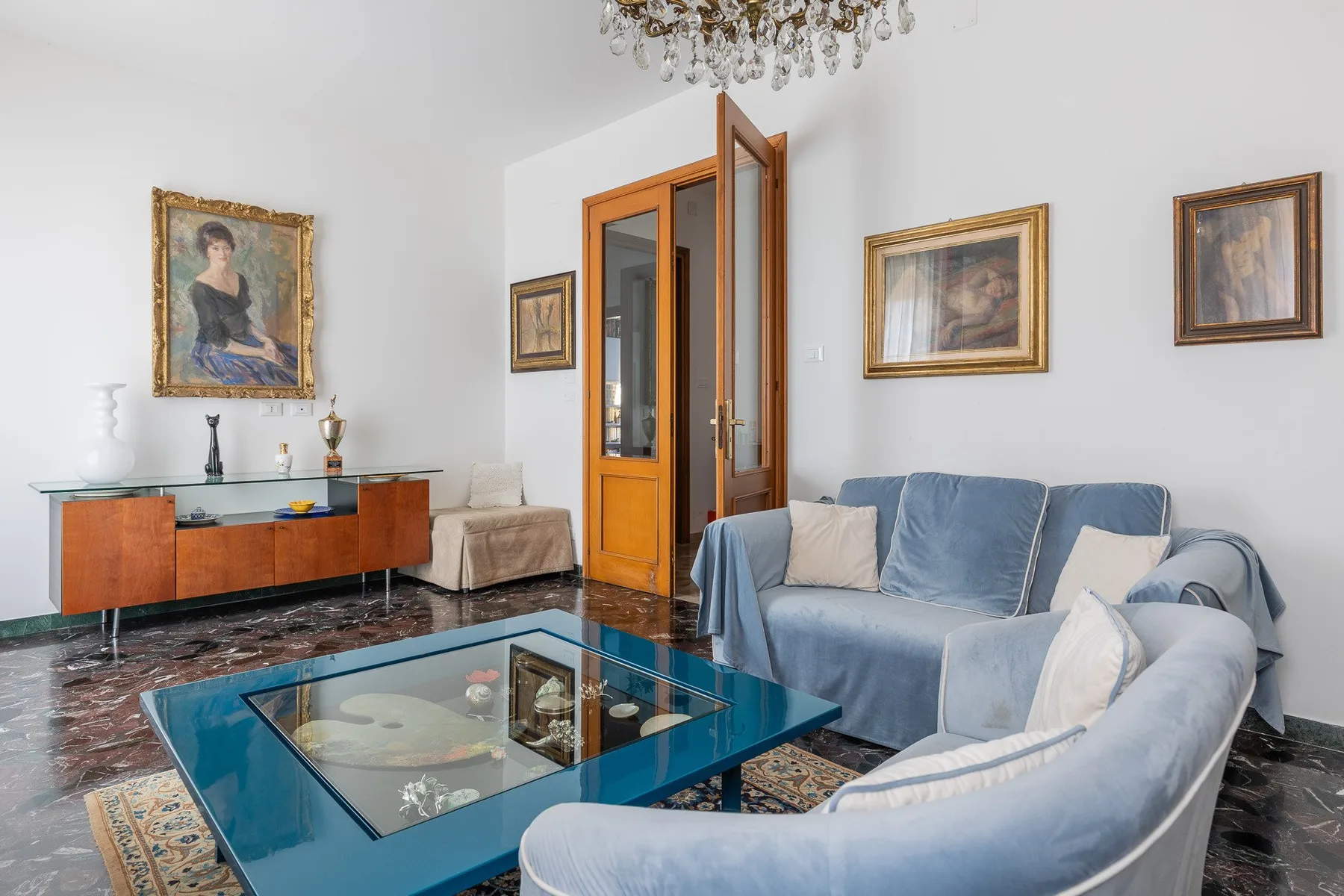 Una sala luminosa con asientos azules y una mesa de centro con cubierta de vidrio.