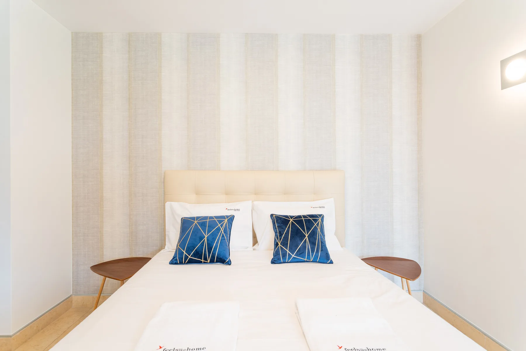 A bright bedroom with a double bed and matching blue pillows.