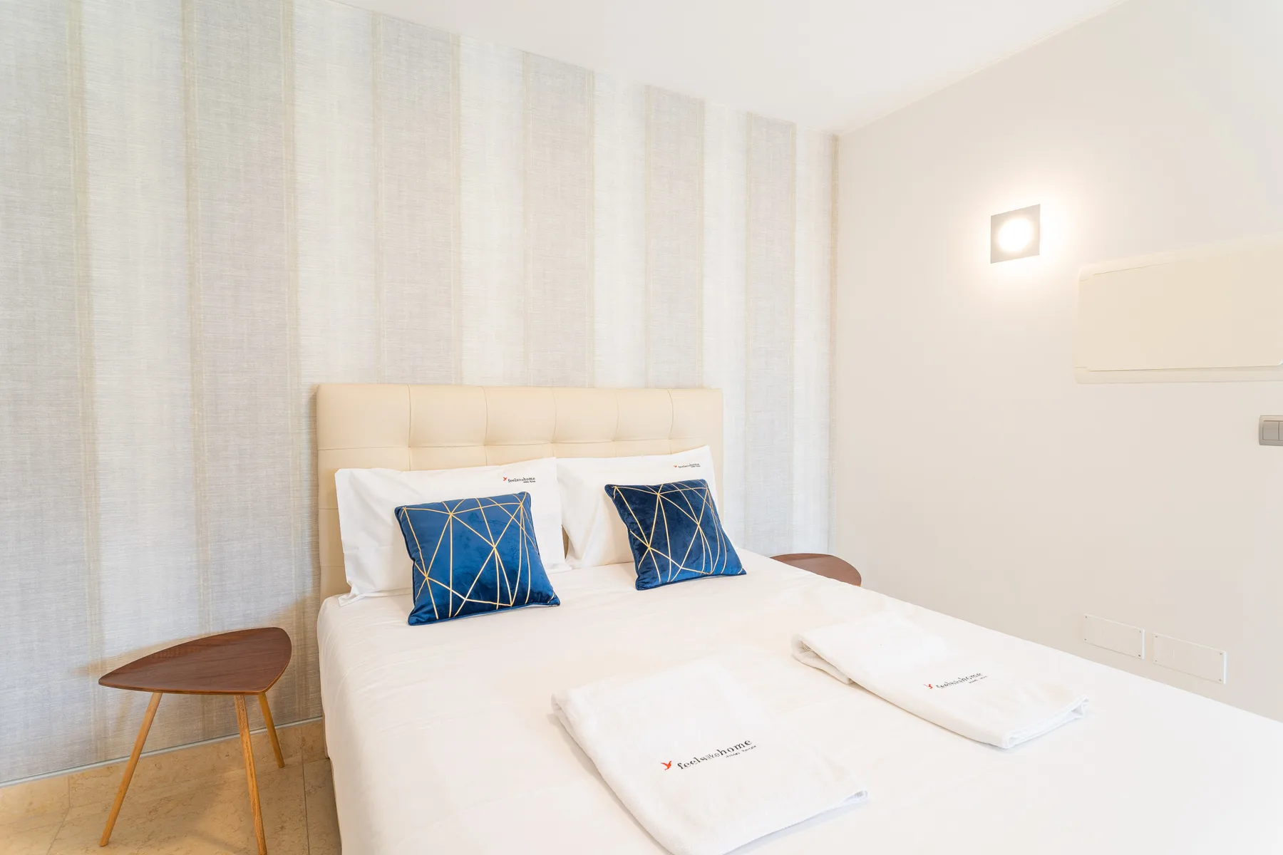 A bedroom with a neatly made bed and blue accent pillows.
