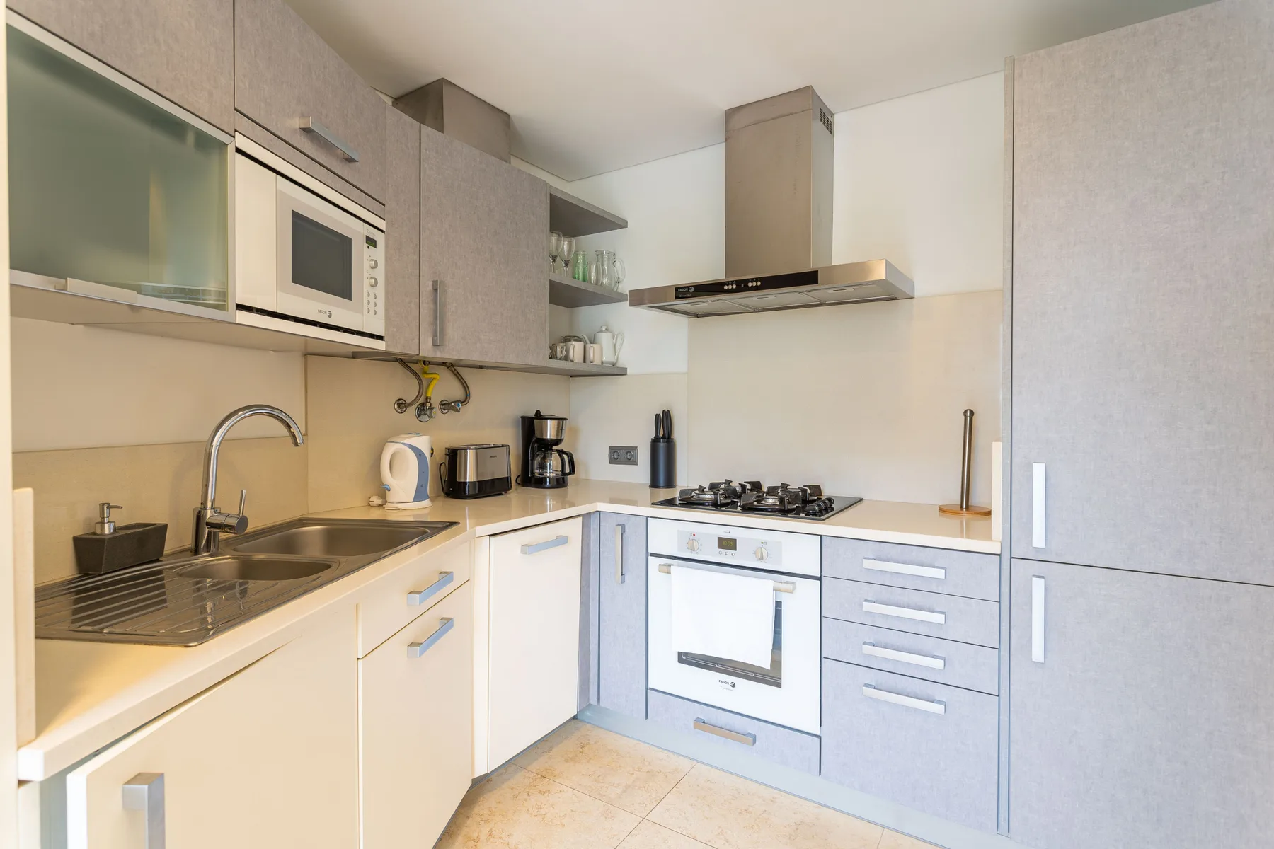 A compact kitchen with a sink, cooktop, and built-in oven.