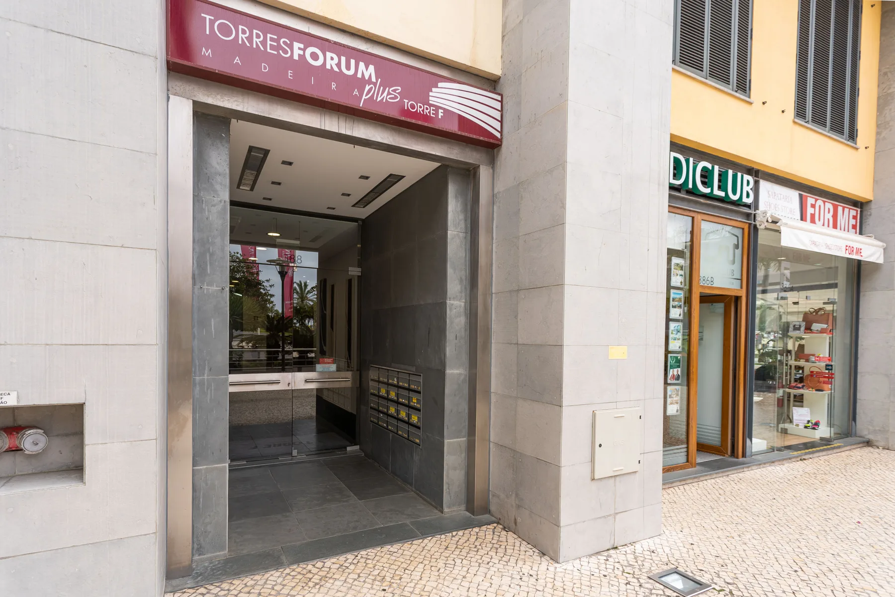A building entrance beside a storefront on a paved pedestrian street.