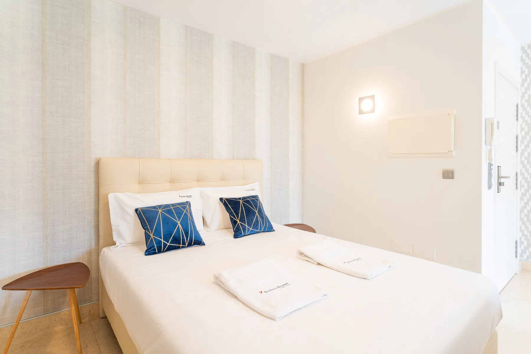 A bright bedroom with a double bed dressed in white linens.