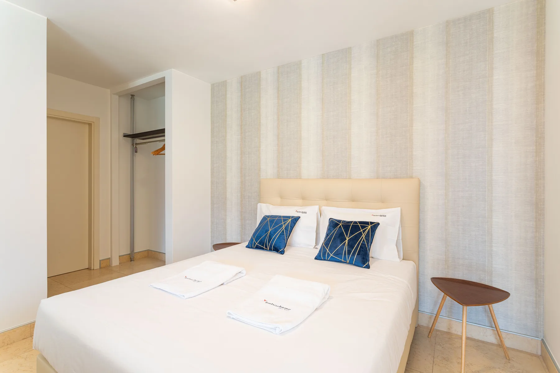 A bedroom with a neatly made bed and two blue accent pillows.