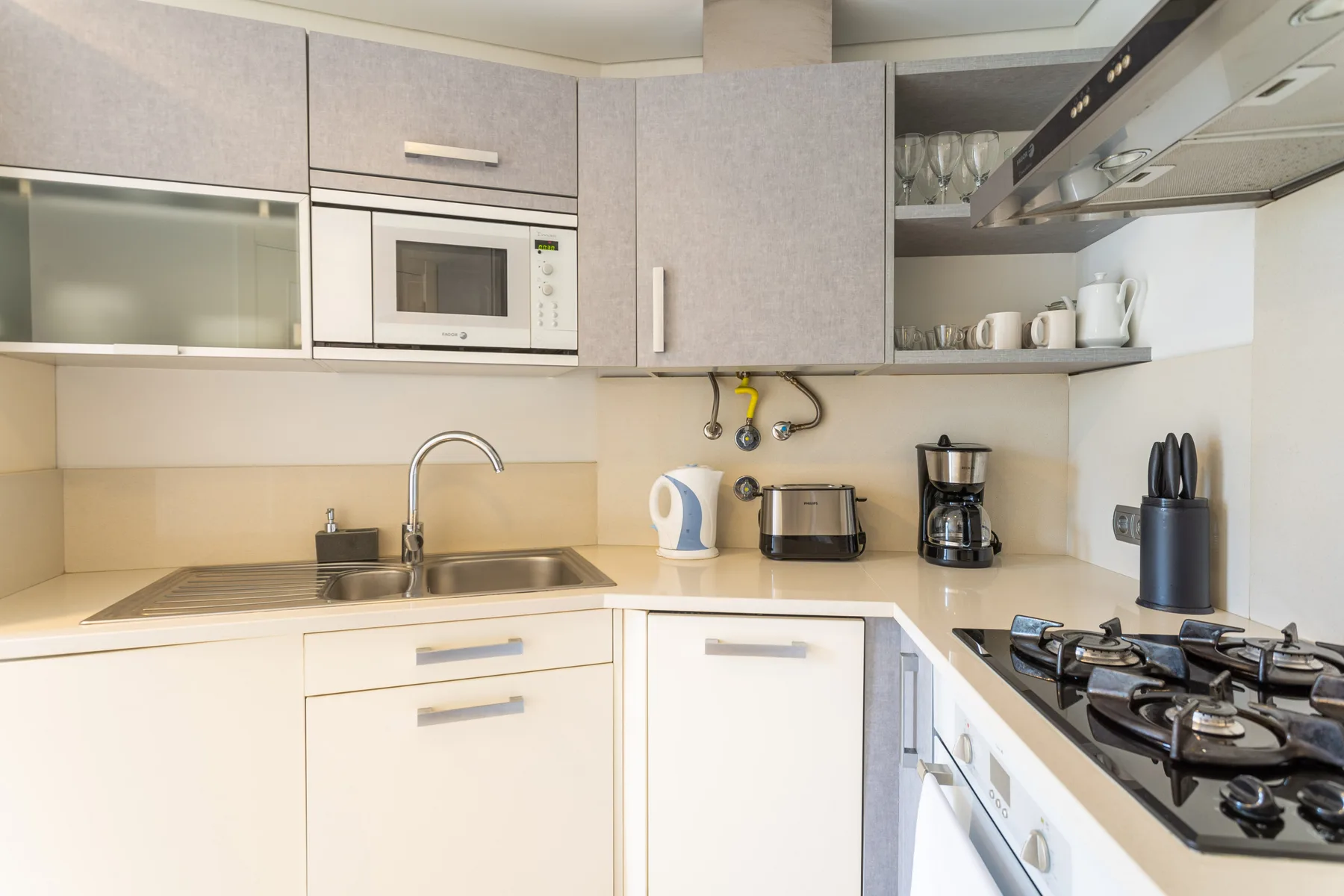 A bright kitchen with a sink, countertop appliances, and a stovetop.
