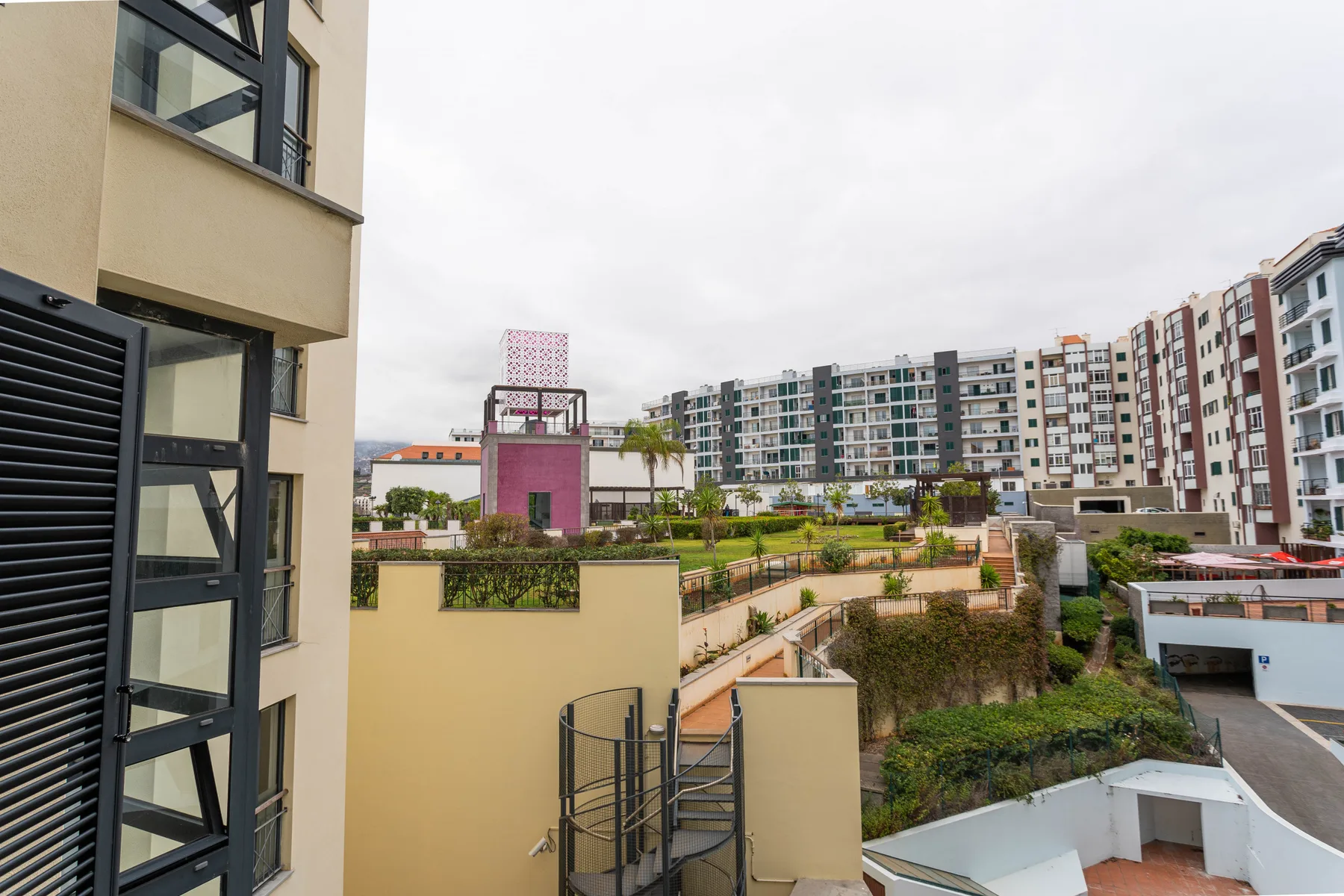 Apartment buildings overlook landscaped grounds and walkways under a cloudy sky.