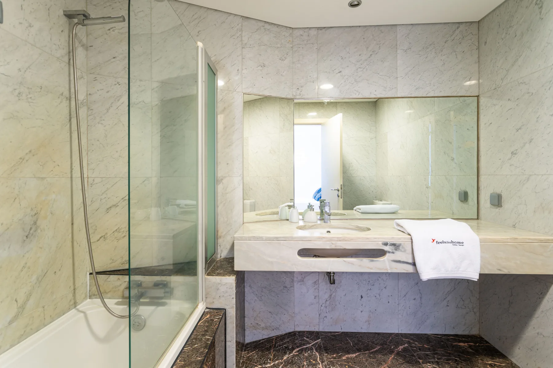 A bright bathroom with a glass shower and a wide sink counter.