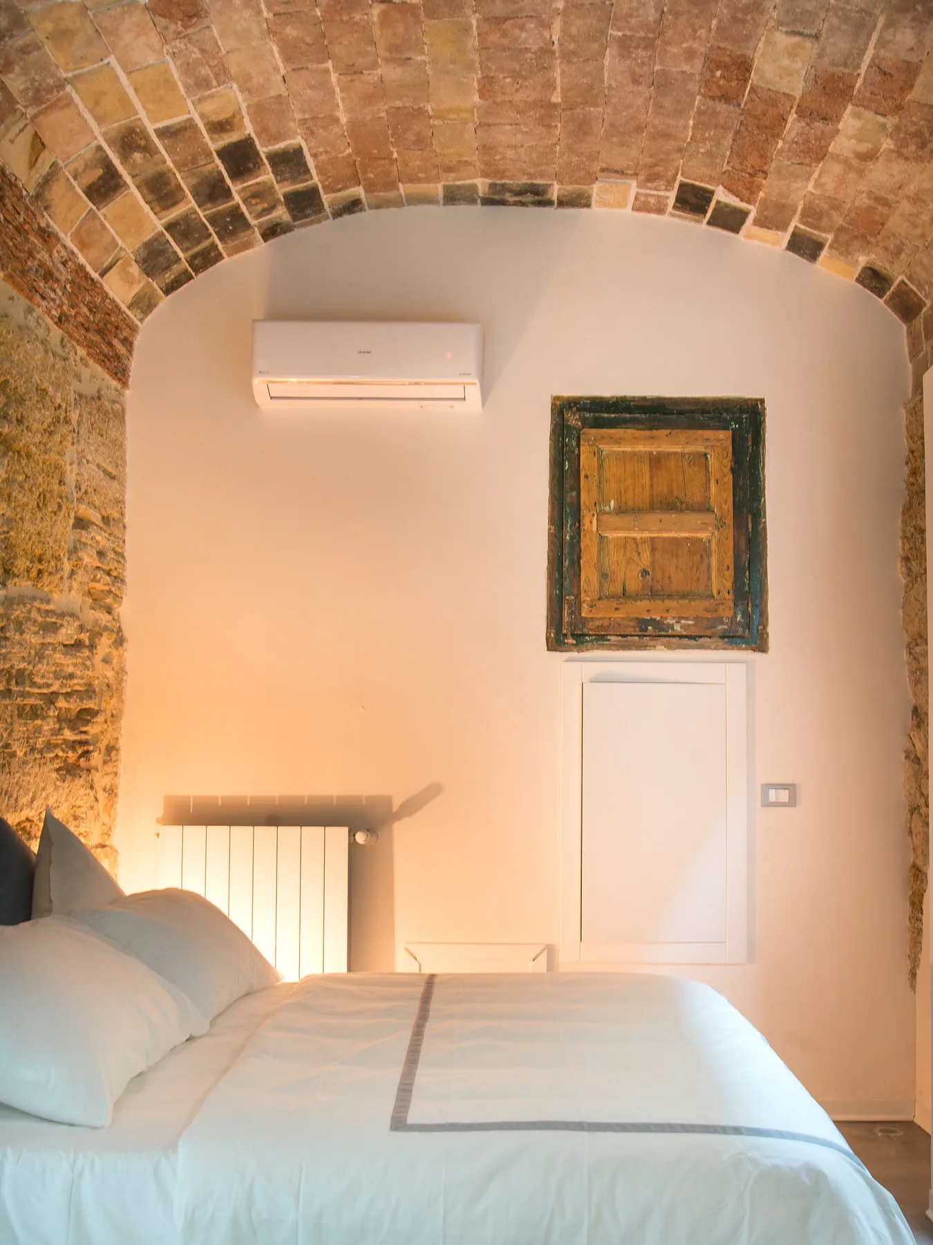 A bedroom with a bed beneath a curved brick ceiling.