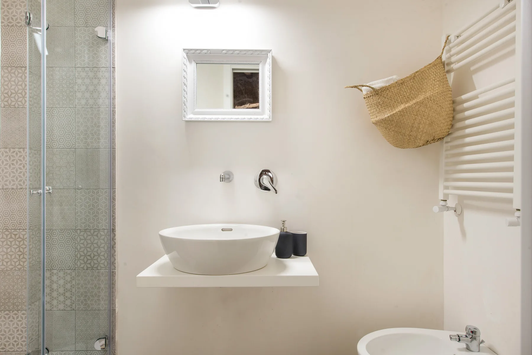 A bright bathroom with a basin, mirror, and glass shower.