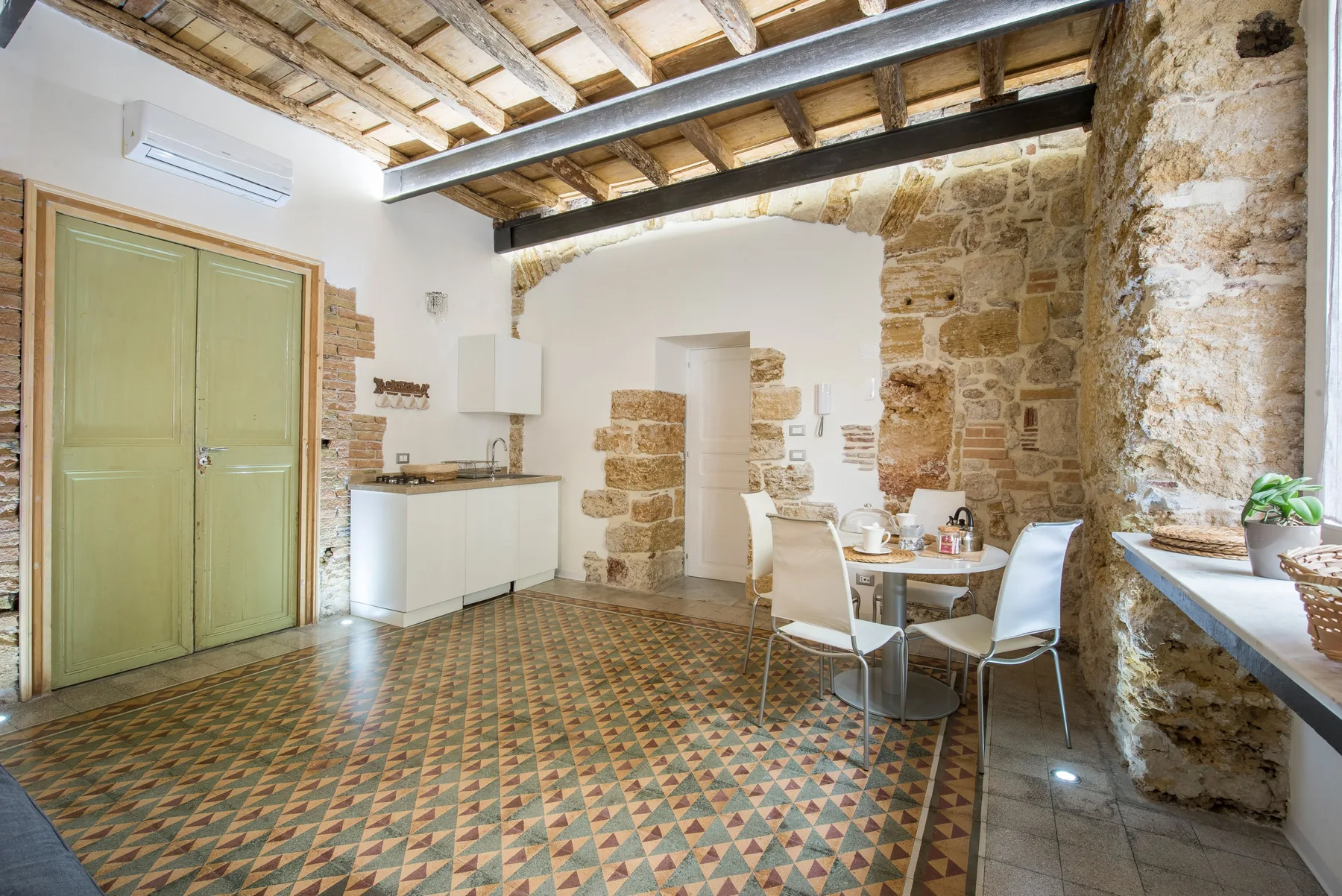 A rustic kitchen and dining area with exposed beams and a patterned tile floor.