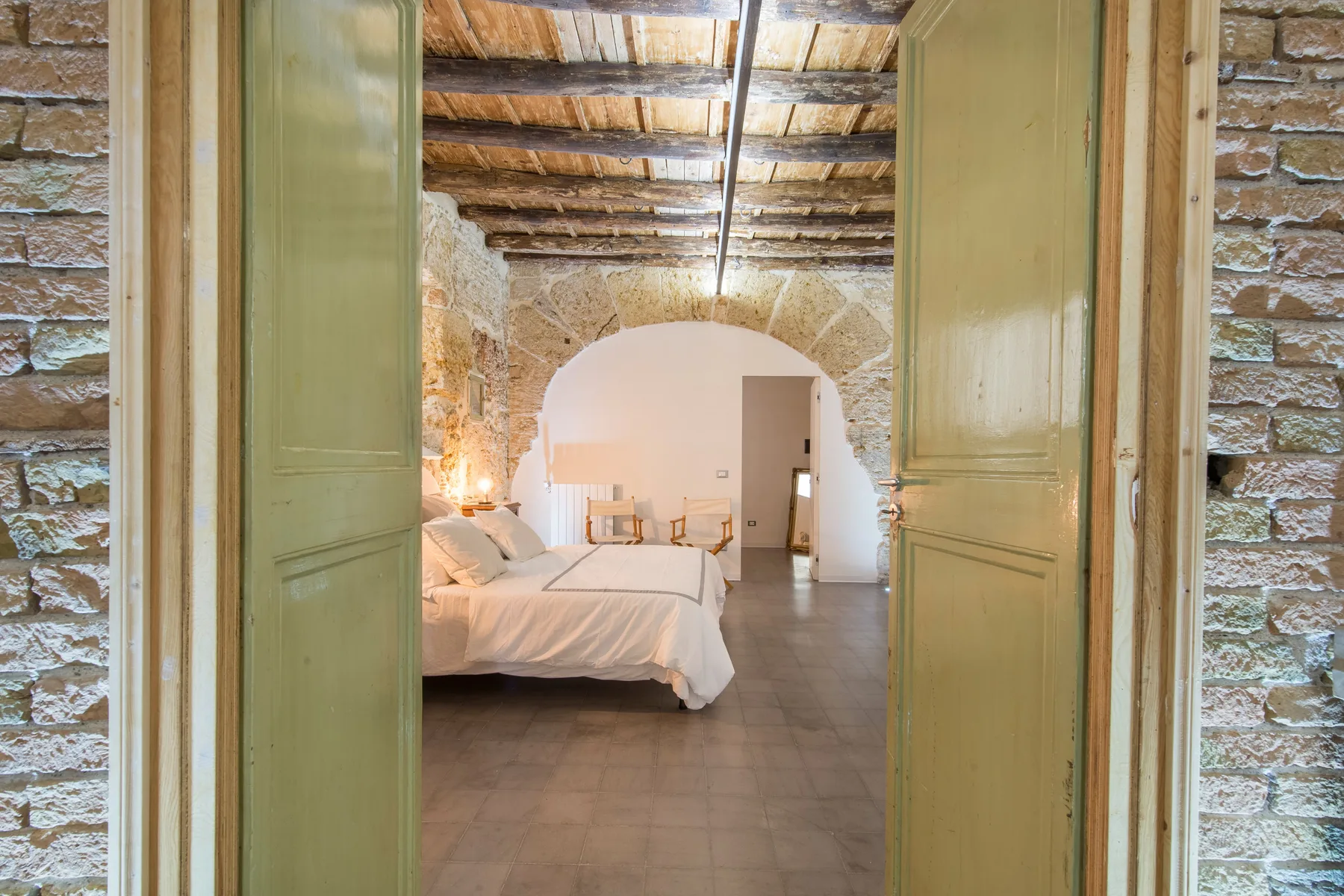 A bedroom with a bed and an arched stone opening.