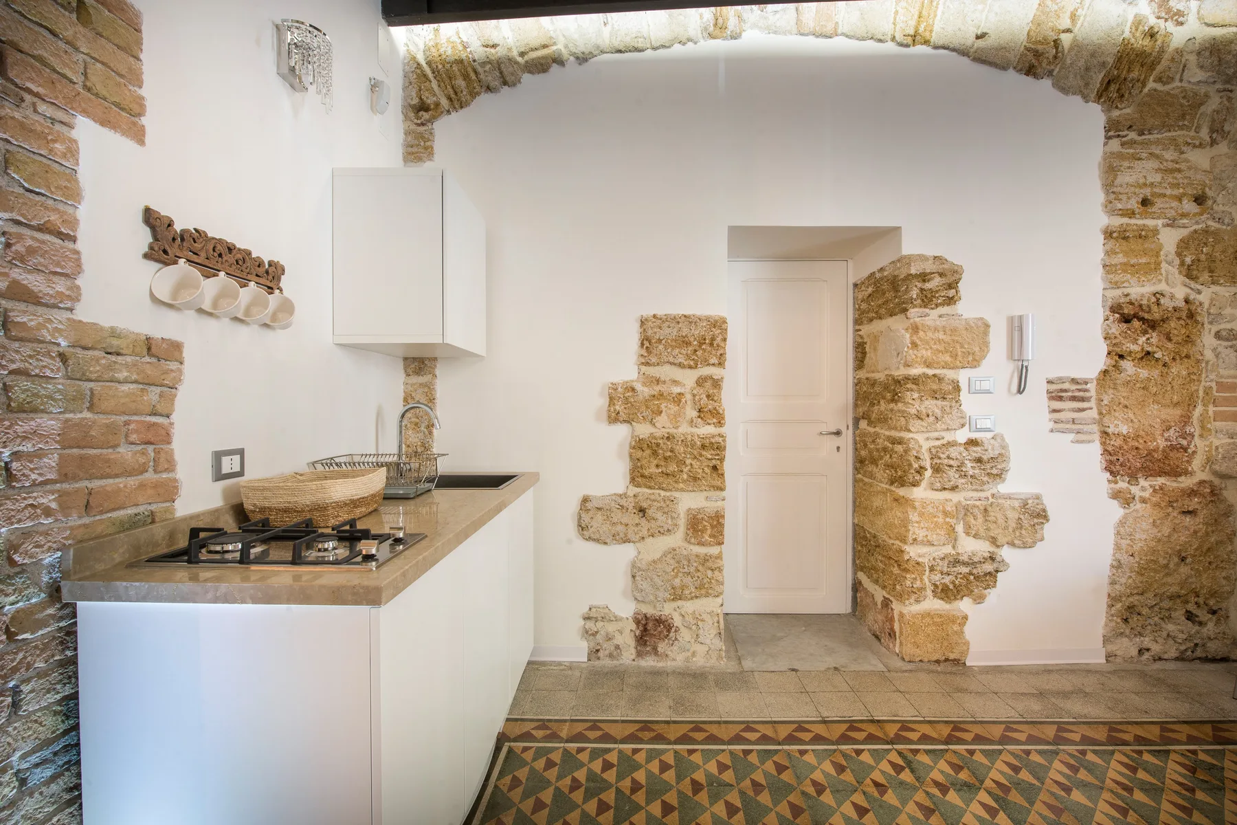 A compact kitchen area with a countertop, cooktop, and exposed stonework.