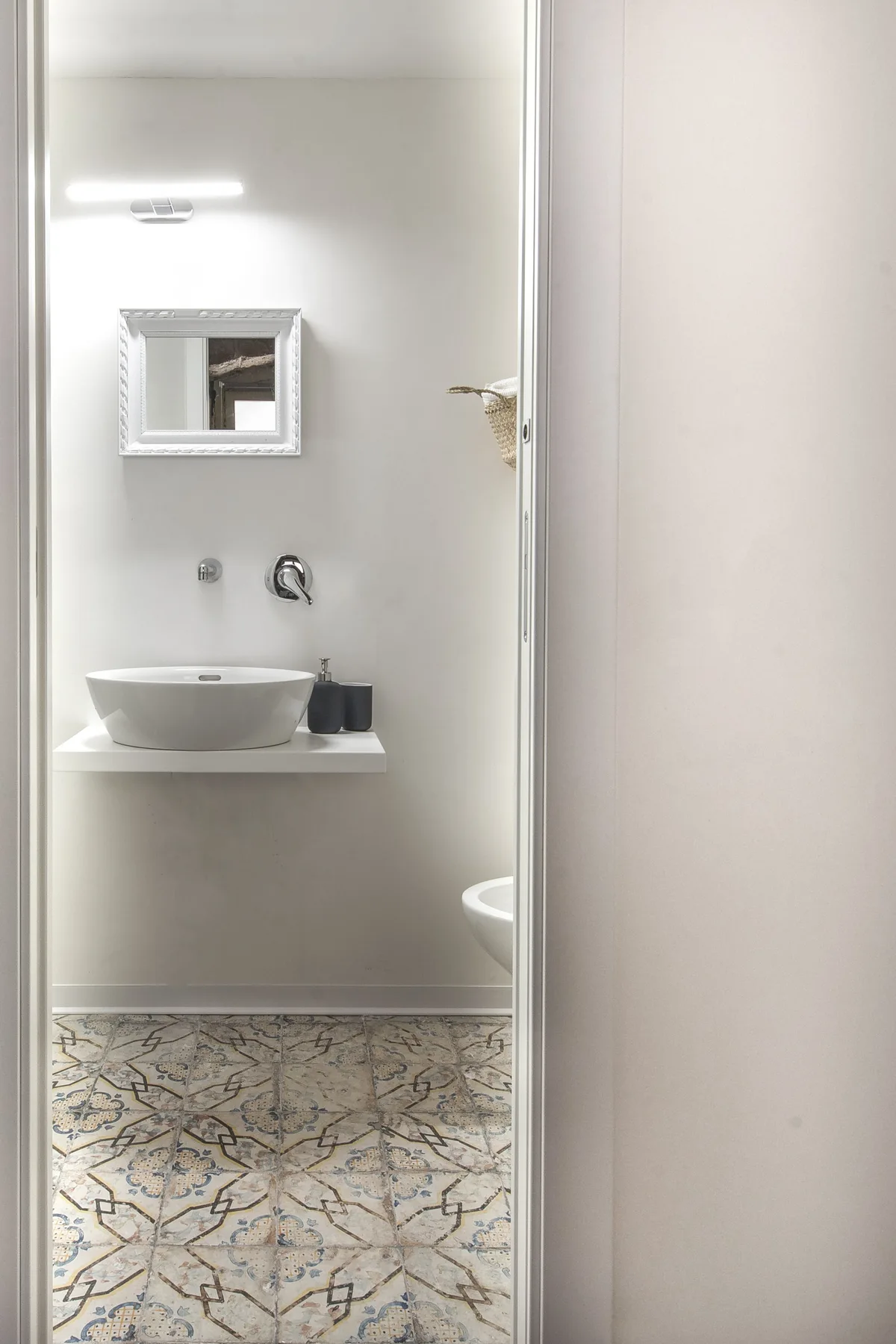 A bathroom vanity with a vessel sink and patterned floor tiles.