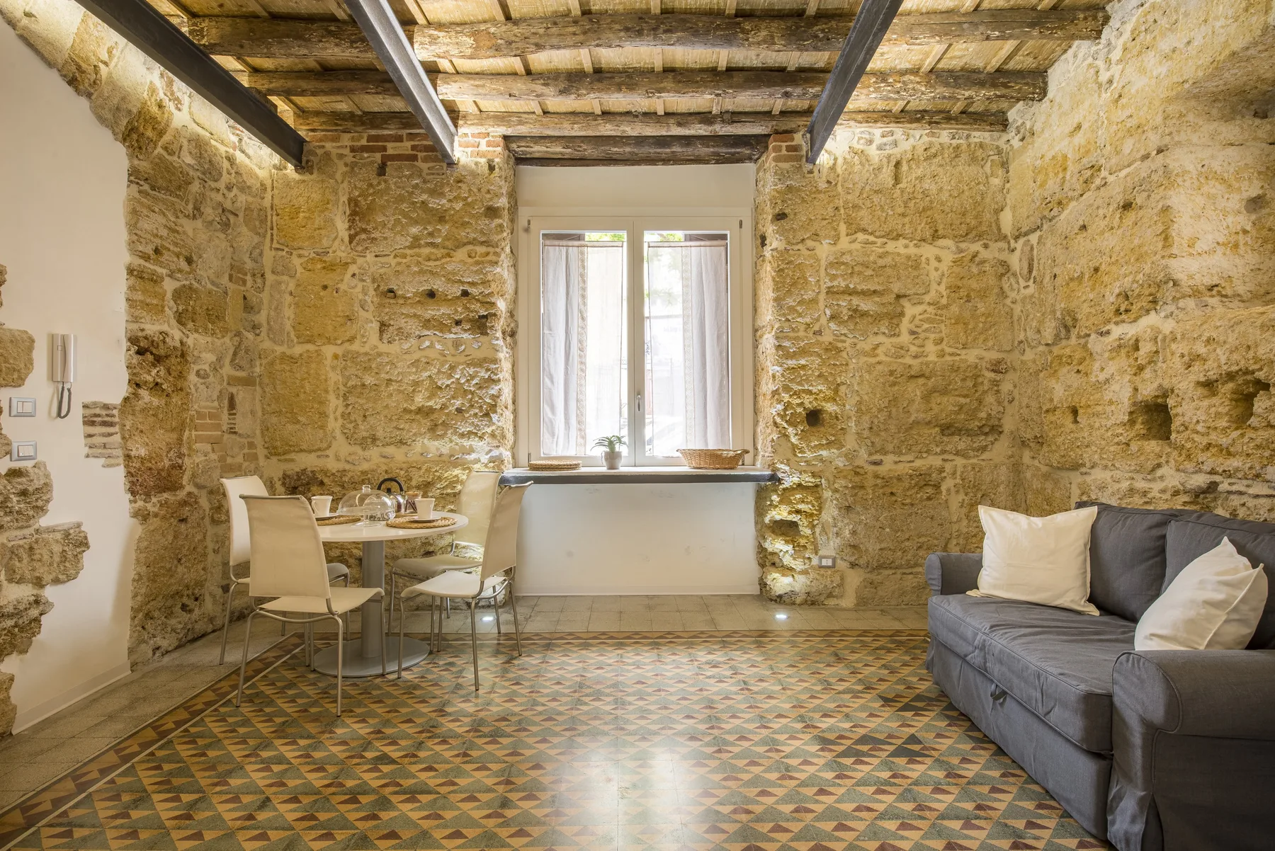 A stone-walled living area with a window, dining table, and seating.