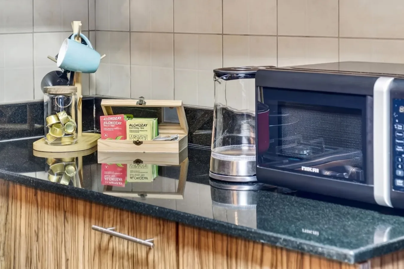 Una encimera de cocina con microondas, hervidor y artículos para preparar té.