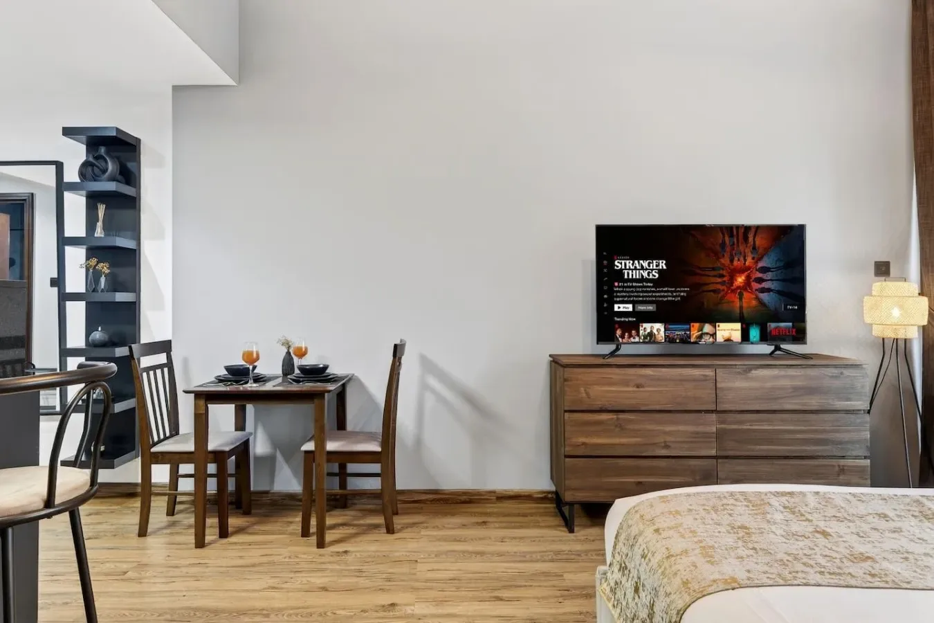 A bedroom with a television on a dresser, a small dining table, and a bed.