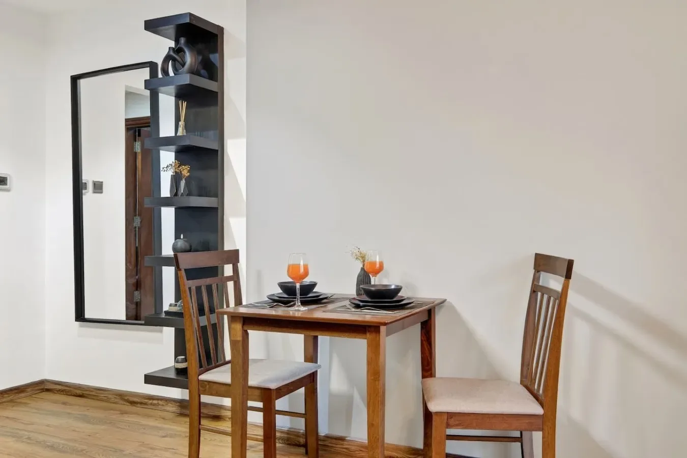 Una pequeña zona de comedor con una mesa preparada con platos y bebidas.