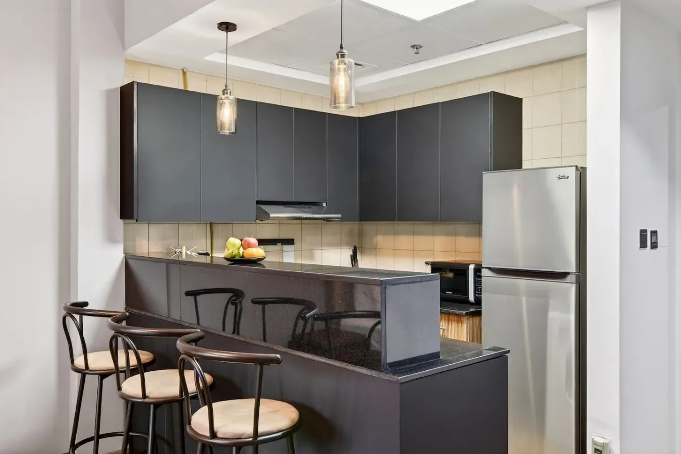 Una cocina moderna con gabinetes oscuros, una barra y asientos.