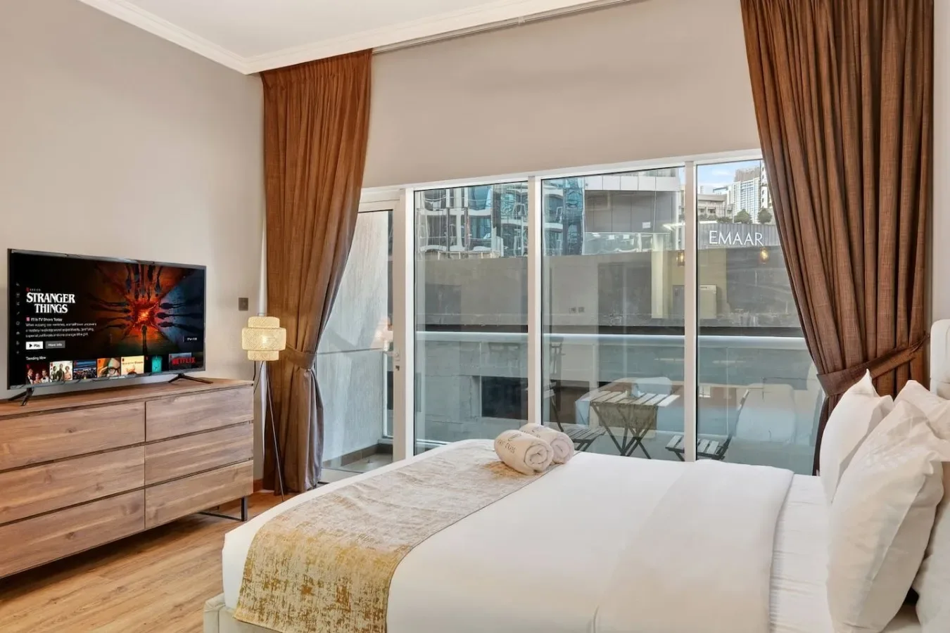 Un dormitorio con cama, televisor y puertas de vidrio que dan a un balcón.