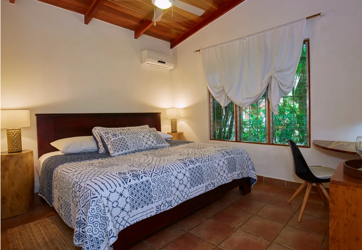 Habitación con cama king de madera, mesas de noche, escritorio y ventilador de techo.