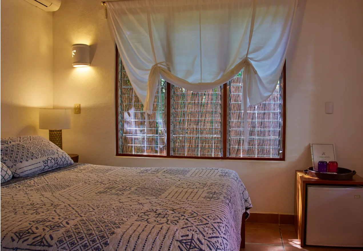 Habitación con cama queen, una colcha estampada y una ventana con vistas a una cerca de bambú.