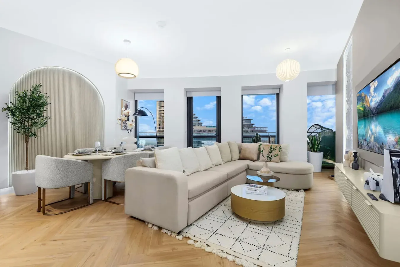 Una luminosa sala de estar con sofá seccional, mesa de comedor y grandes ventanas.