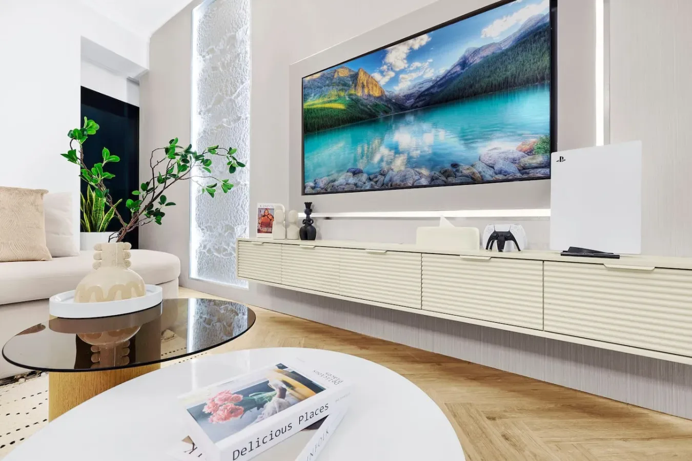 Una sala luminosa con un televisor grande sobre un mueble largo.