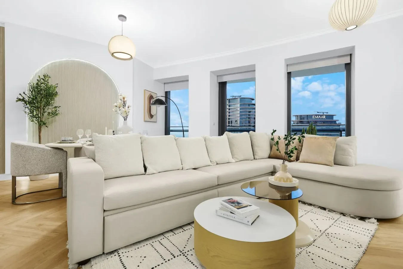 A bright living room with a large sectional sofa and round coffee tables.