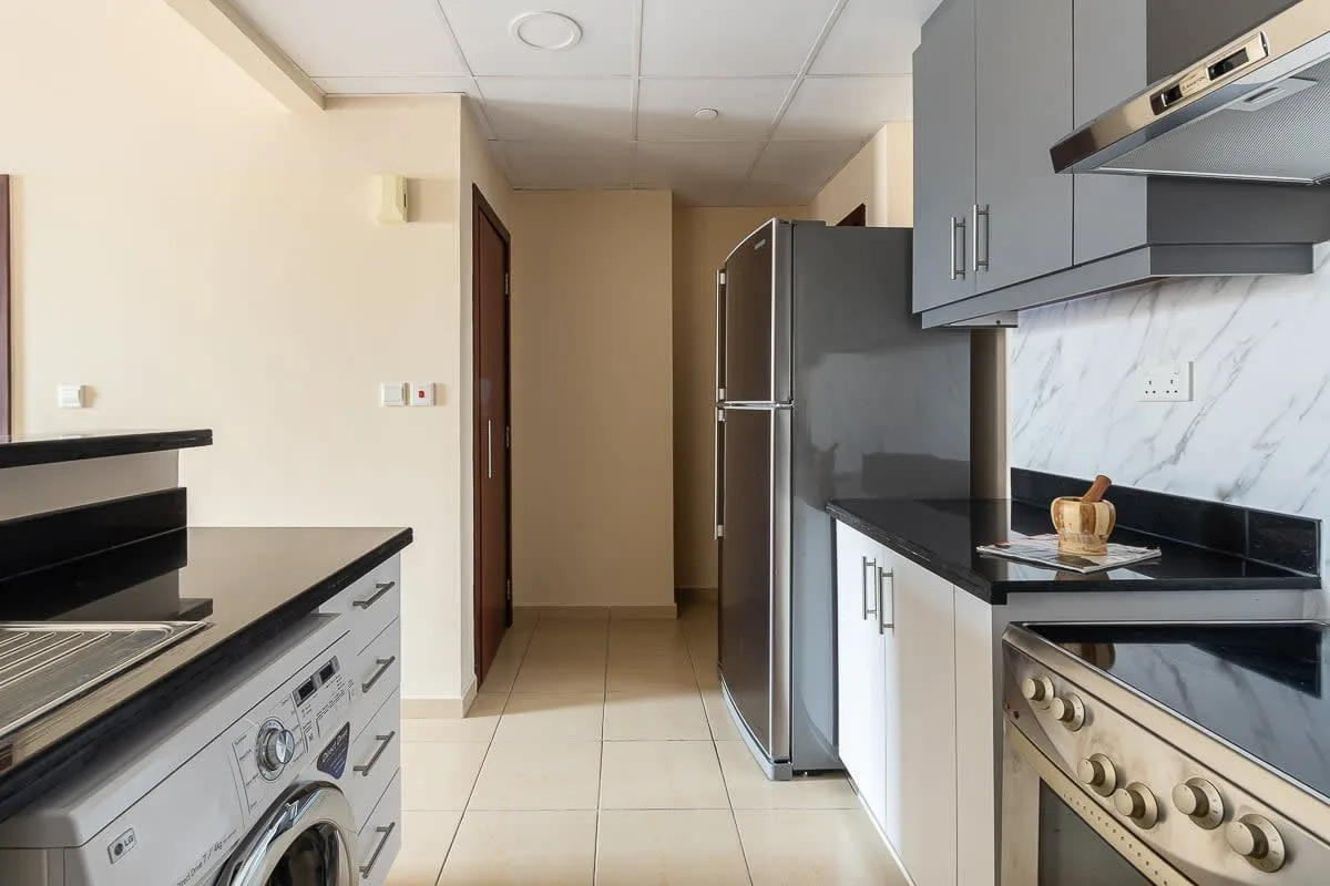 Una cocina compacta con encimeras oscuras, un refrigerador y una estufa.