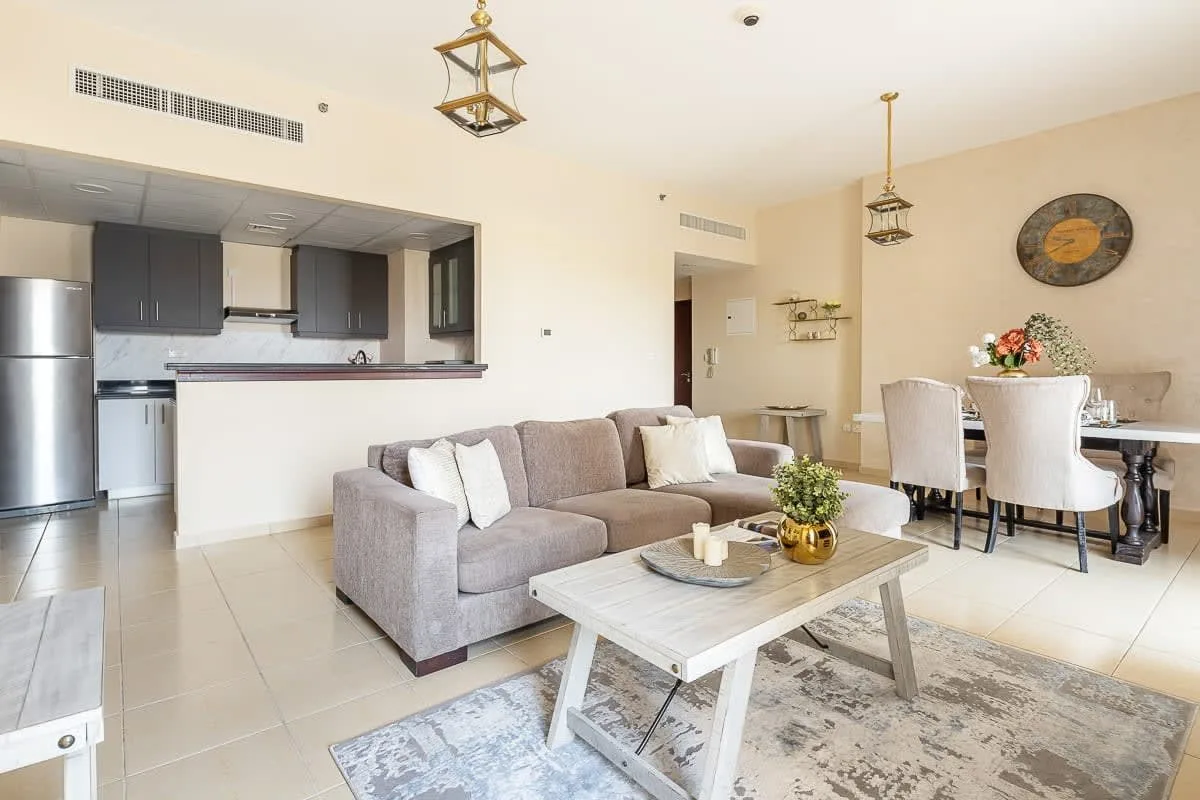 Una sala-comedor de planta abierta con un sofá gris y una mesa de comedor.