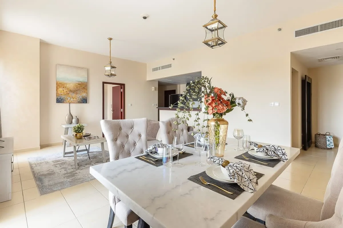 Un comedor abierto con la mesa puesta, un centro floral y asientos.