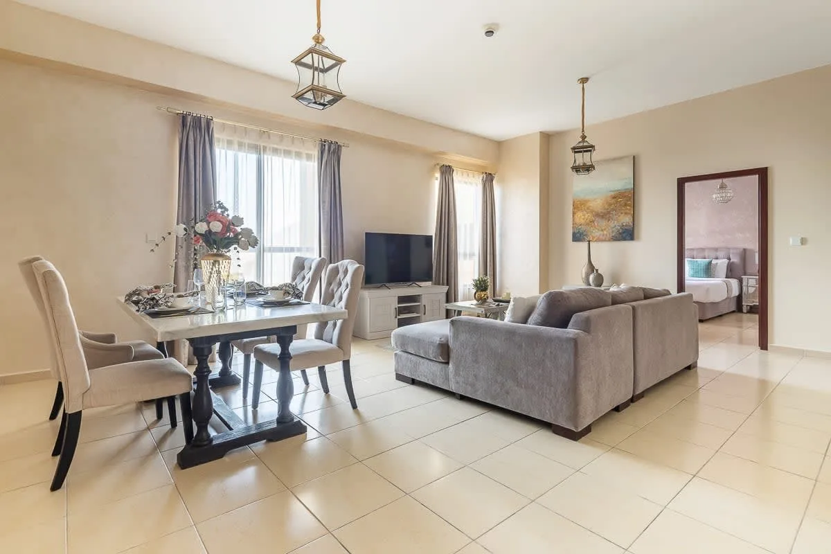 Una sala de estar y comedor con una mesa y asientos junto a un televisor.