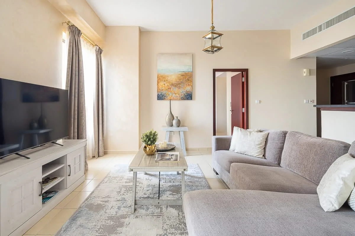 Una sala luminosa con asientos, una mesa de centro y un televisor.