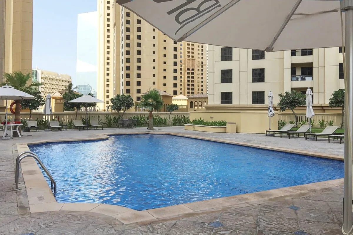 Una piscina al aire libre está junto a asientos y edificios de apartamentos altos.